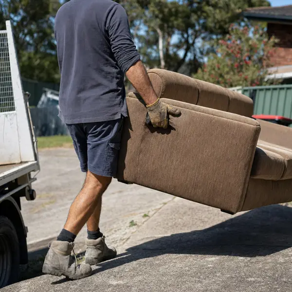 An old lounge being carried down a driveway to the truck